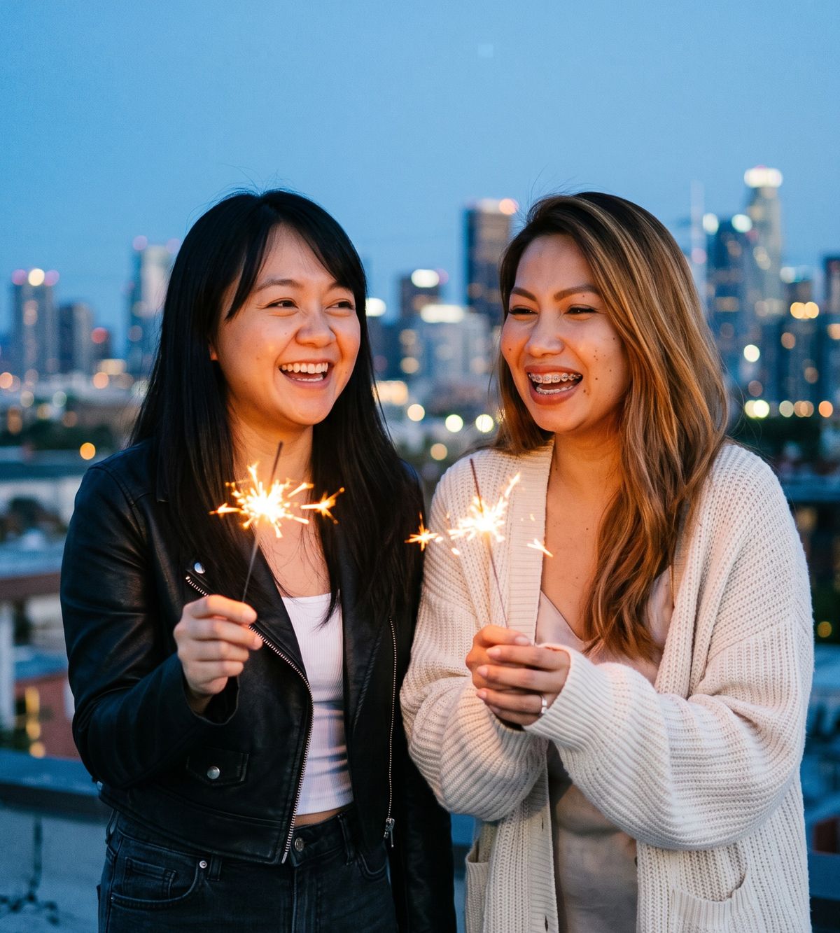 Dimple and Machu holding sparklers on a rooftop at dusk